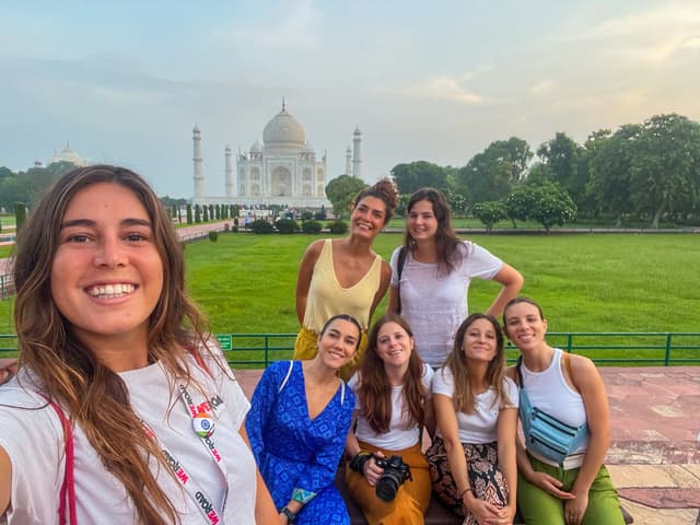 Des femmes souriantes d'un groupe WeRoad prennent un selfie devant le Taj Mahal.