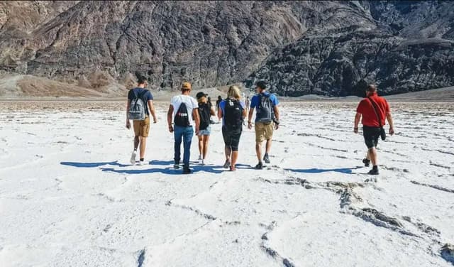 Un grupo de WeRoad camina por un salar blanco al pie de una montaña.